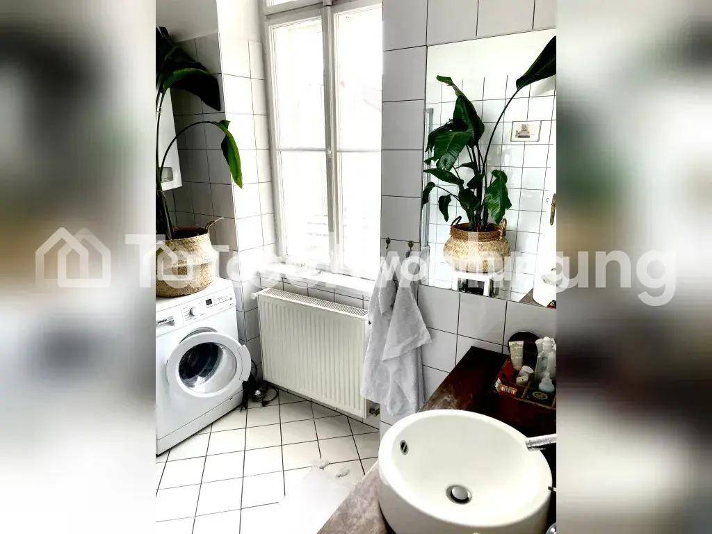 Helles Badezimmer mit weißen Fliesen, Waschbecken, Waschmaschine und einem Fenster für Tageslicht.