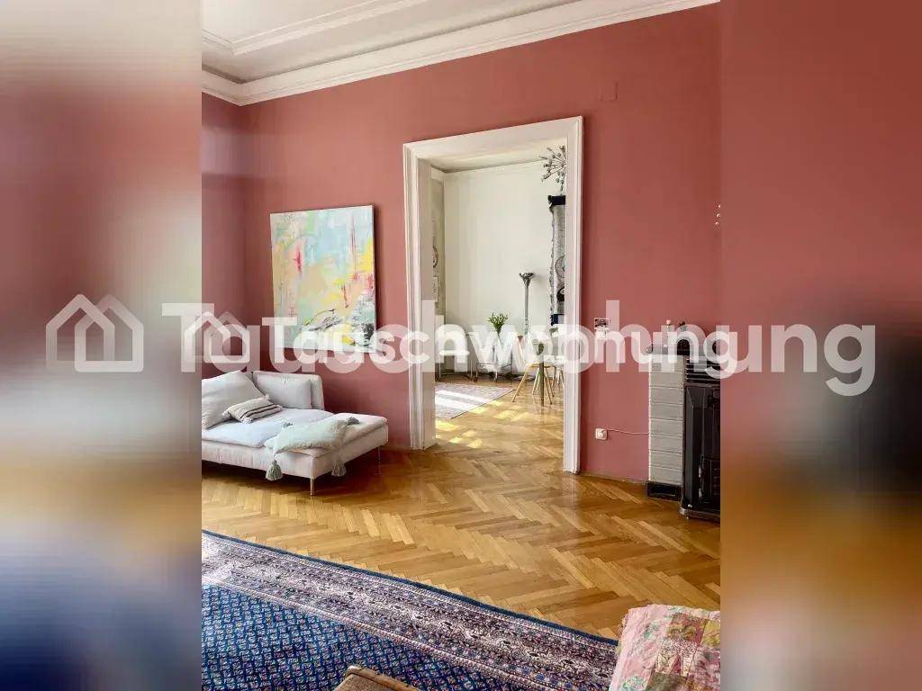 Geräumiges Wohnzimmer mit rosa Wänden, Fischgrätparkett und offenem Zugang zu einem weiteren Raum.