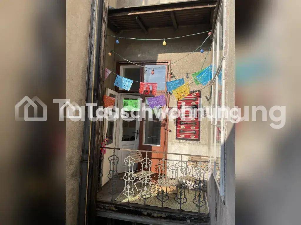 Kleiner Balkon mit schmiedeeisernem Geländer, dekoriert mit bunten Wimpelketten.