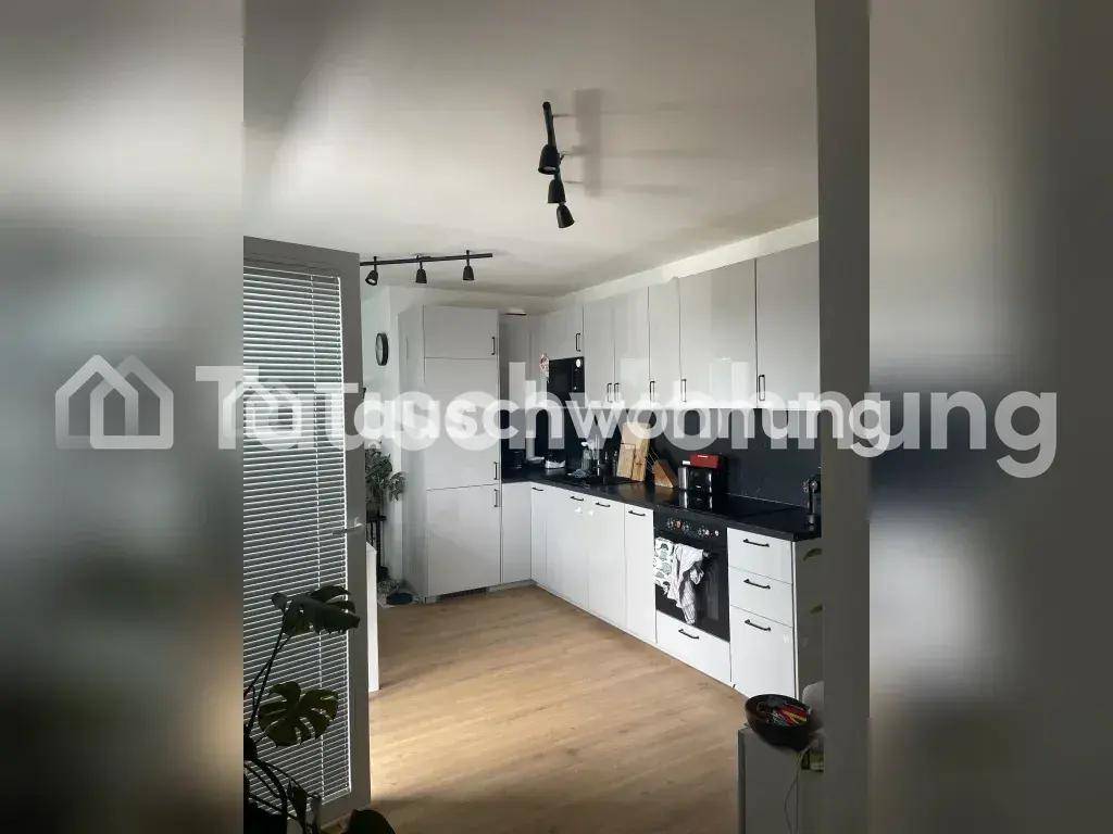 Moderne Küche mit hellgrauen Schränken, dunkler Arbeitsplatte und integrierten Geräten.
