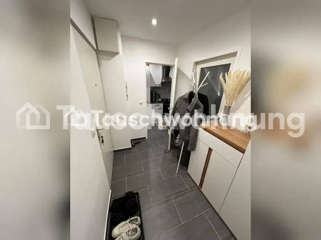 Heller Eingangsbereich mit grauen Fliesen, Garderobe und Schuhablage.