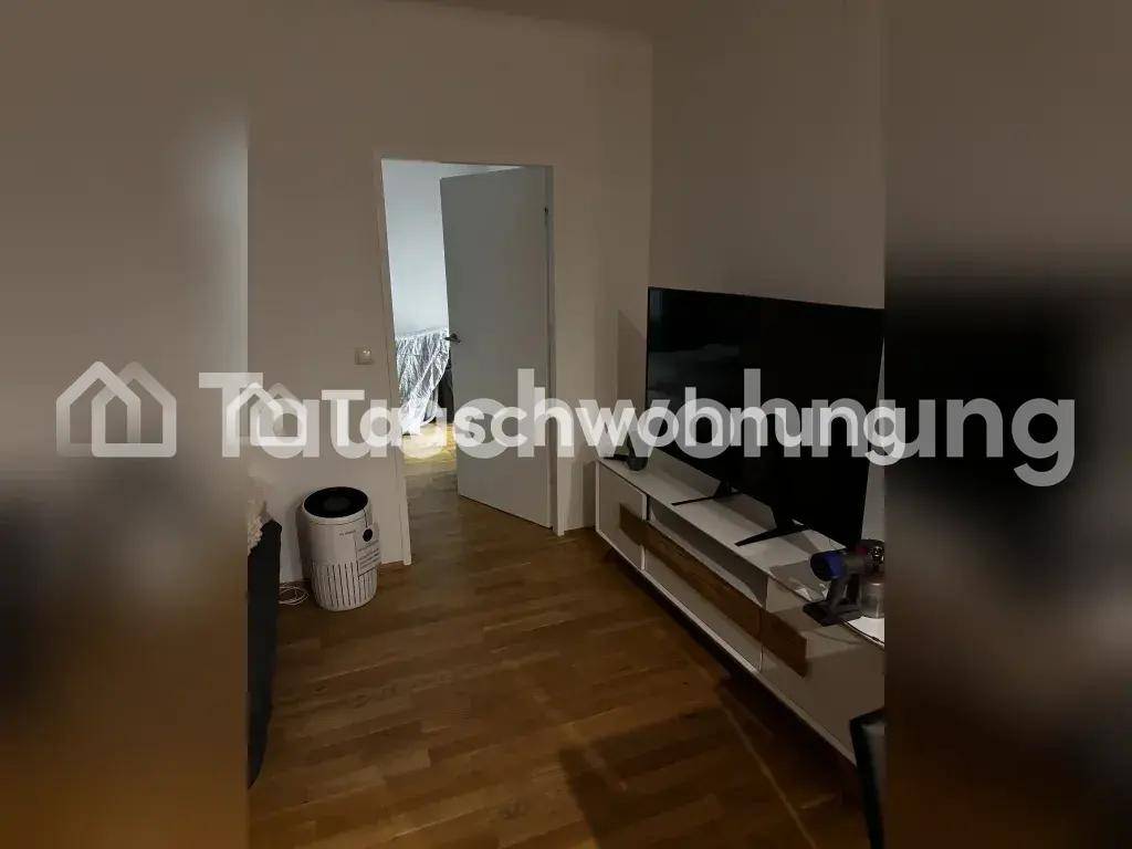 Wohnzimmer mit Fernseher auf einem Sideboard und Blick in einen angrenzenden Raum.