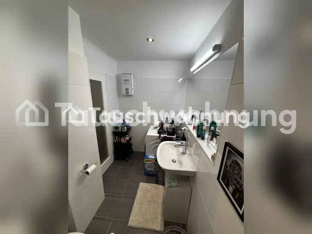 Modernes Badezimmer mit Waschbecken, Toilette, Waschmaschine und Fliesenboden.
