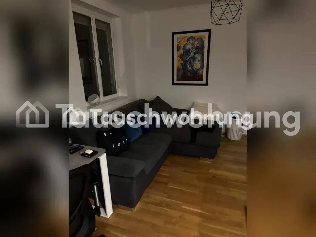 Gemütliches Wohnzimmer mit dunklem Ecksofa, Holzfußboden und einem Fenster.