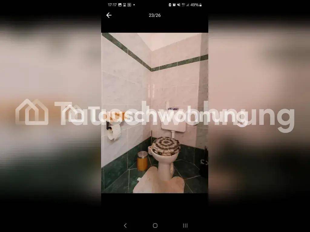 Kleines WC mit Toilette und Waschbecken, gefliest in Grün und Weiß.