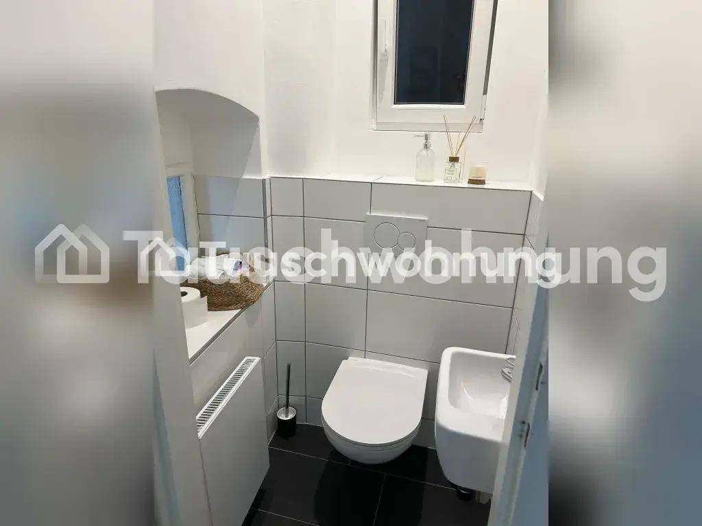 Helles Gäste-WC mit wandhängendem WC, kleinem Waschbecken und Fenster.