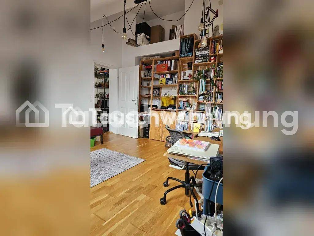 Arbeitsbereich im Dachgeschoss mit großem Bücherregal, Holzboden und Dachschräge.