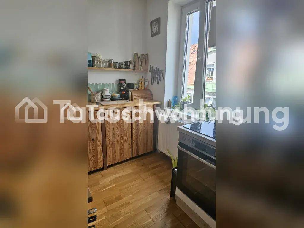 Küche mit Holzschränken, Herd und Fenster mit Blick nach draußen, hell und praktisch.