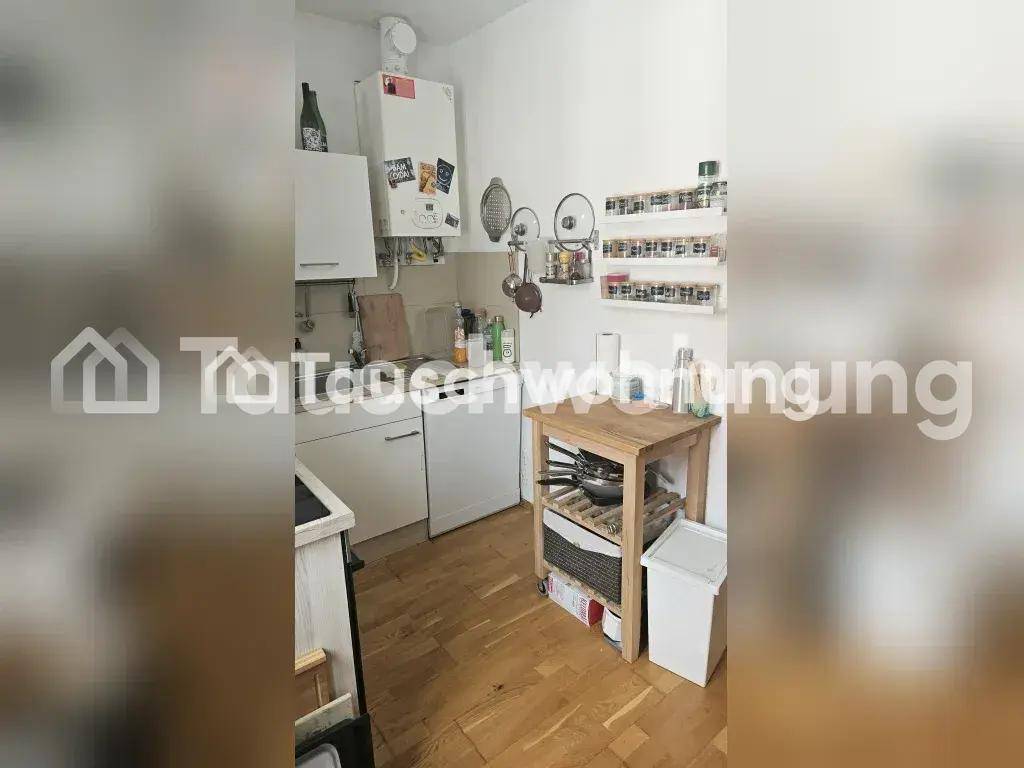 Kompakte Küche mit weißen Schränken, Spüle und kleinem Beistelltisch, gut organisiert.