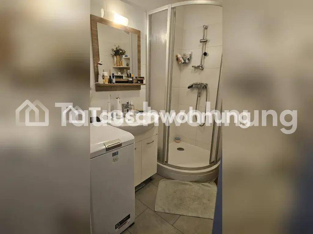 Badezimmer mit Dusche, Waschbecken, Spiegel und Waschmaschine, praktisch eingerichtet.