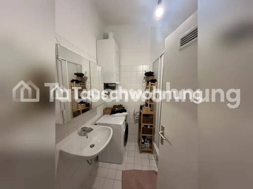 Funktionales Badezimmer mit Dusche, Waschbecken und Waschmaschine, gefliest.