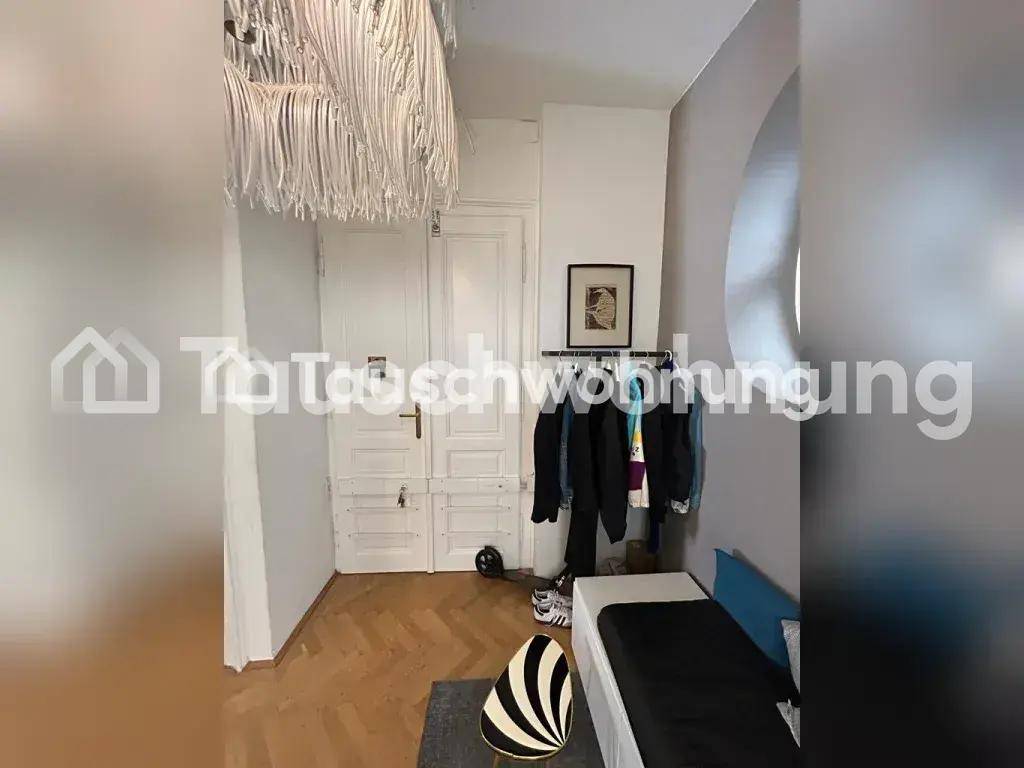 Kleines Schlafzimmer mit Einzelbett, Kleiderstange und Fischgrätparkett, beleuchtet von einer Deckenleuchte.
