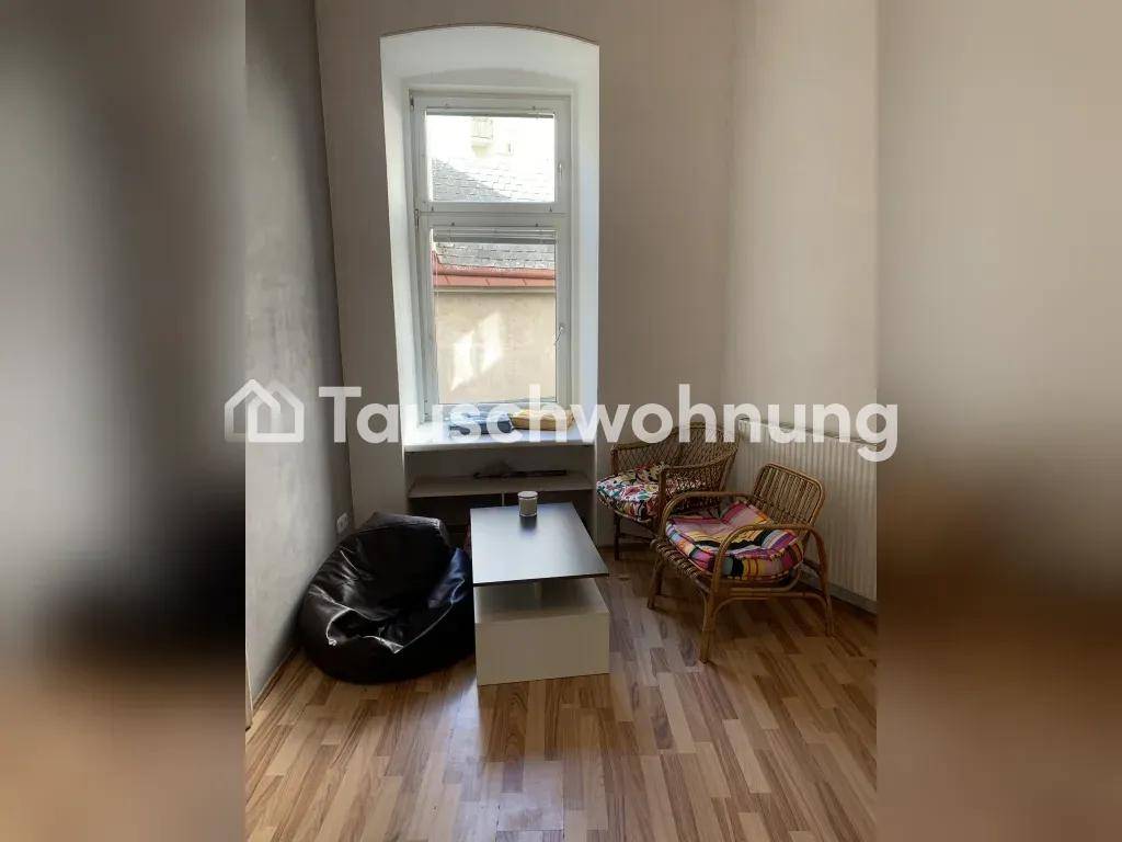 Gemütlicher Wohnbereich mit großem Fenster, modernen Sitzgelegenheiten und hellem Laminatboden.