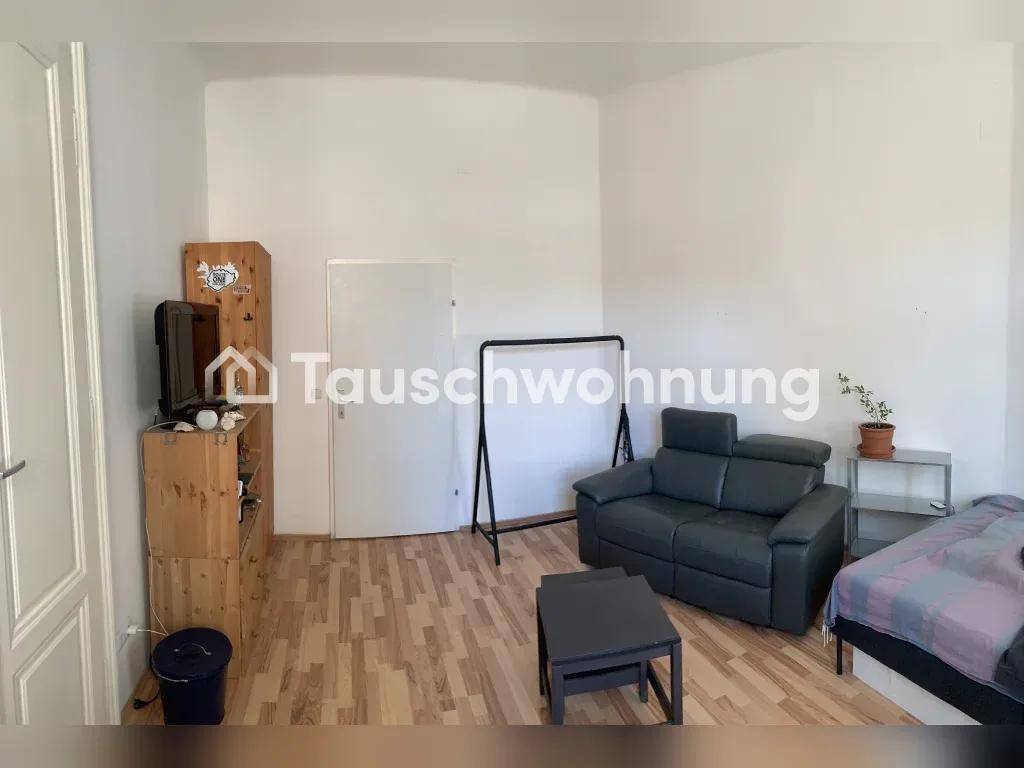 Heller Wohnbereich mit Sofa, Bett und Laminatboden, funktional und modern eingerichtet.
