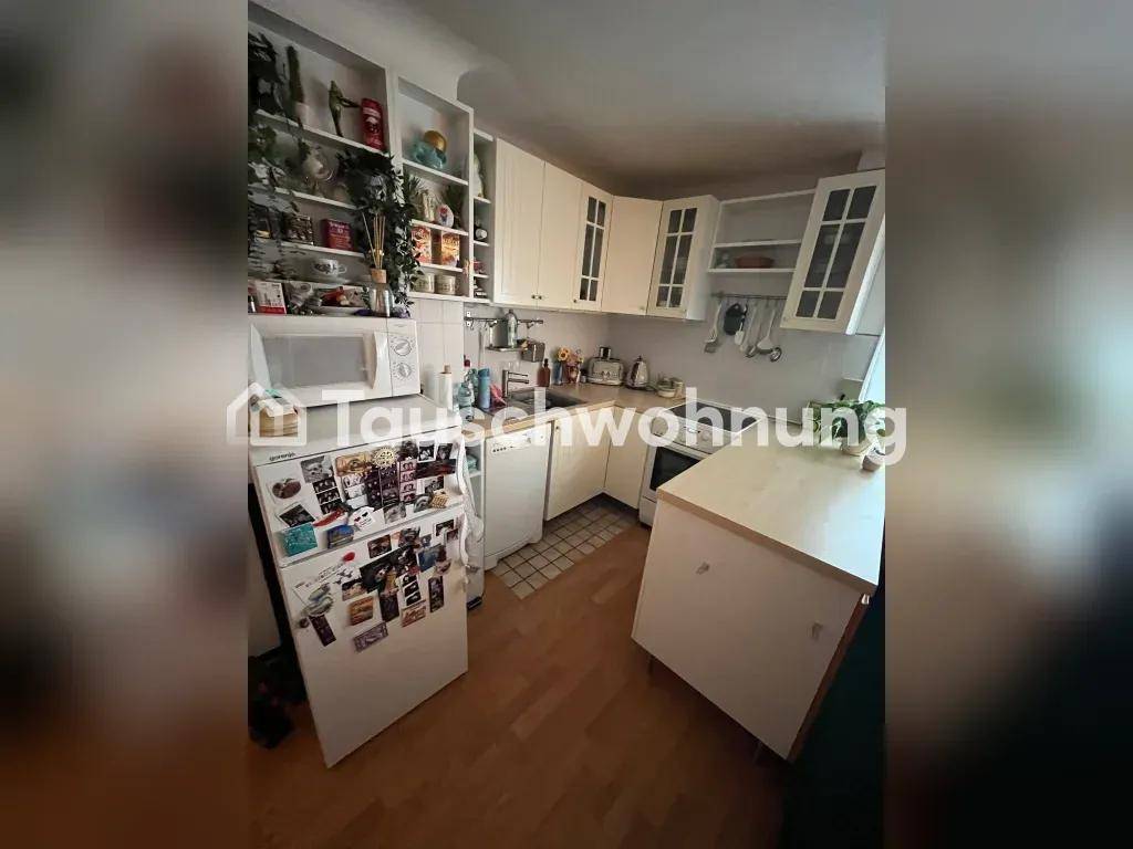 Funktionale Küche mit weißen Schränken, Kühlschrank und integrierter Waschmaschine.