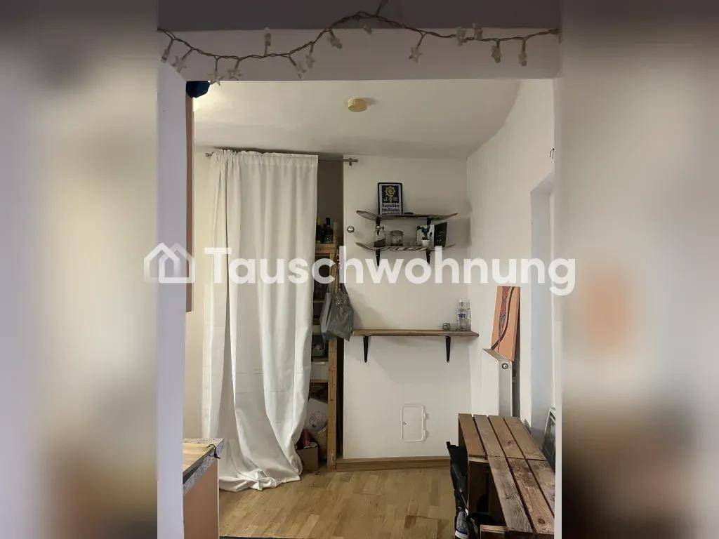 Kleiner Raum mit Holzboden, einfachen Regalen und einem Holztisch, der als Essbereich dient.