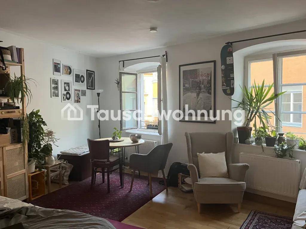 Helles Wohnzimmer mit mehreren Fenstern, Sitzgelegenheiten, Pflanzen und einem kleinen Esstisch.