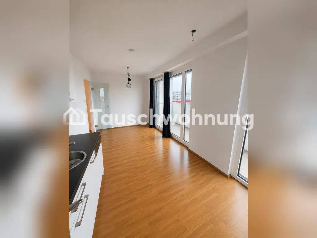 Heller Wohnbereich mit Holzboden, offener Küchenzeile und Zugang zu großen Balkontüren.