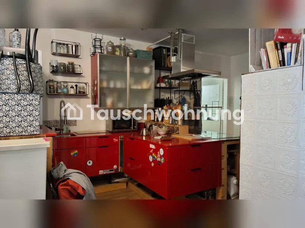 Küche mit roten Unterschränken, Hängeschränken und einer Dunstabzugshaube über dem Kochbereich.