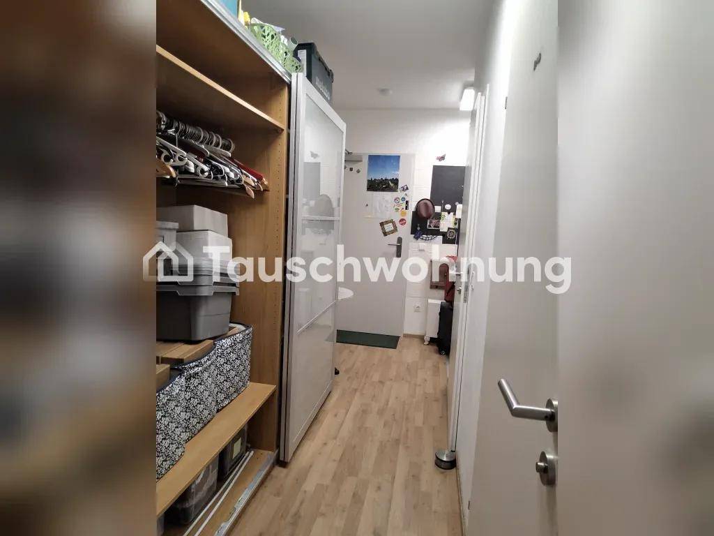 Schmaler Flur mit offenen Regalen für Kleidung und Aufbewahrungsboxen, führt zu einer Tür.