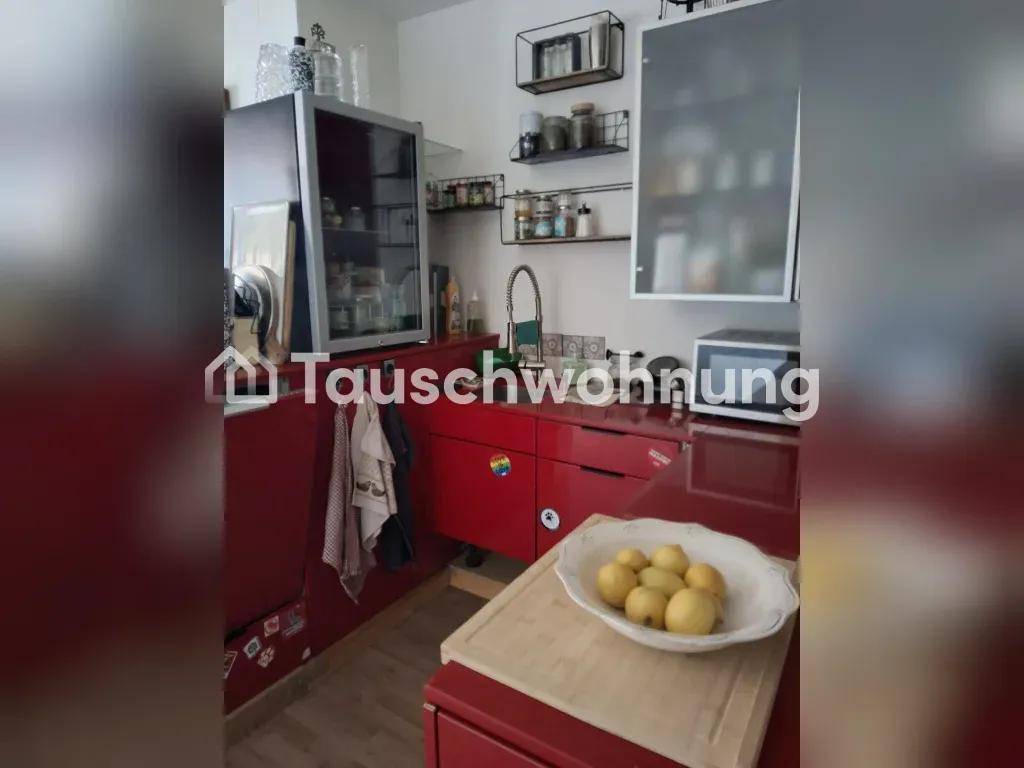 Detailansicht der Küche mit roten Schränken, Spülbecken und einer Schale mit Zitronen auf der Arbeitsplatte.