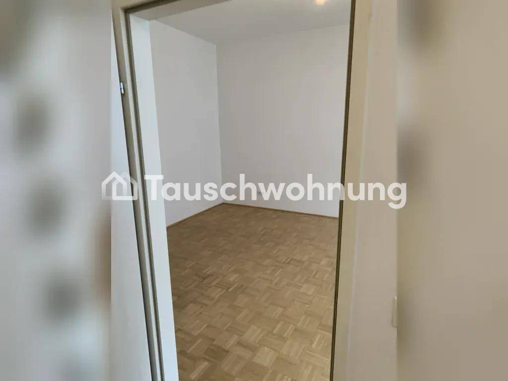 Blick durch eine Tür in einen leeren Raum mit hellem Parkettboden und weißen Wänden.