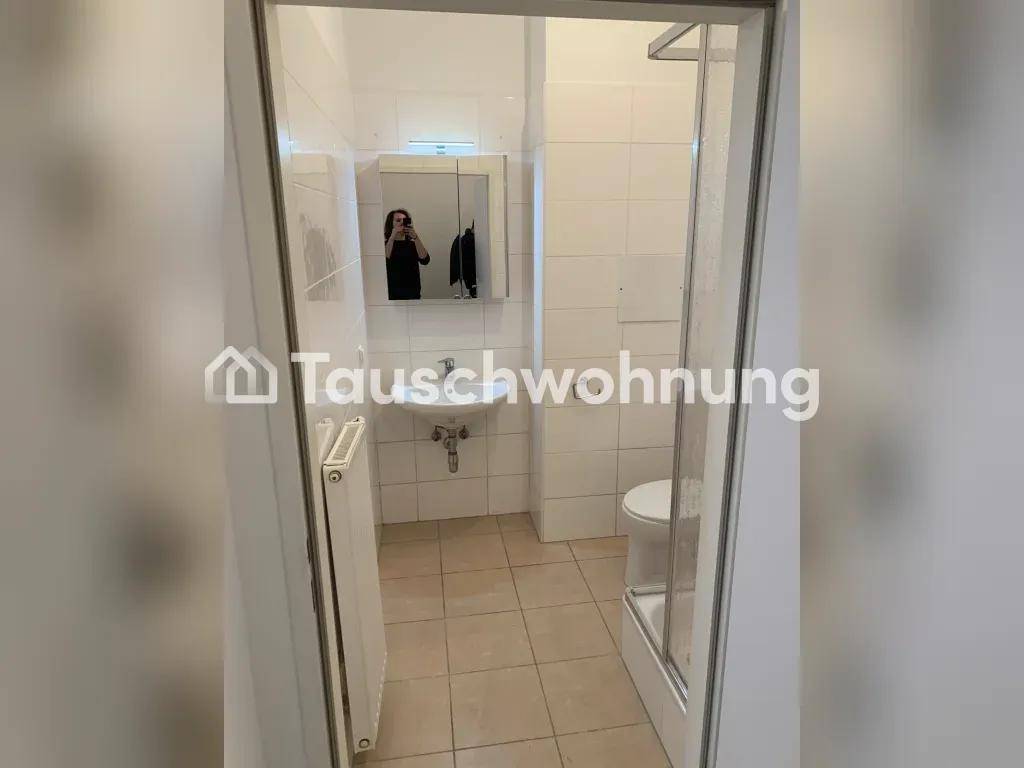Kleines Badezimmer mit weißen Fliesen, Waschbecken, Toilette und Duschkabine.