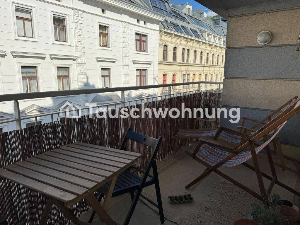 Gemütlicher Balkon mit Holztisch und Stühlen, umgeben von Stadtgebäuden.
