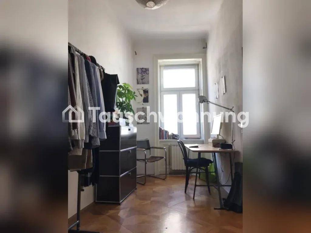 Kleines Zimmer mit Kleiderstange, Schreibtisch und Fenster.