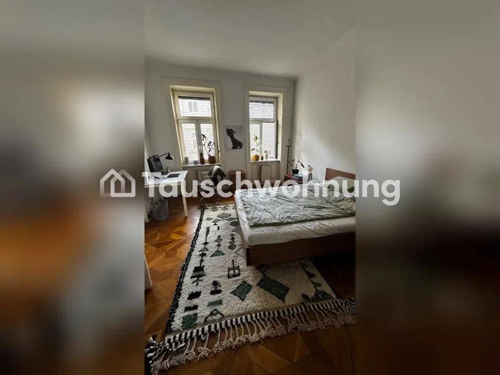 Schlafzimmer mit Bett, Schreibtisch und zwei großen Fenstern.