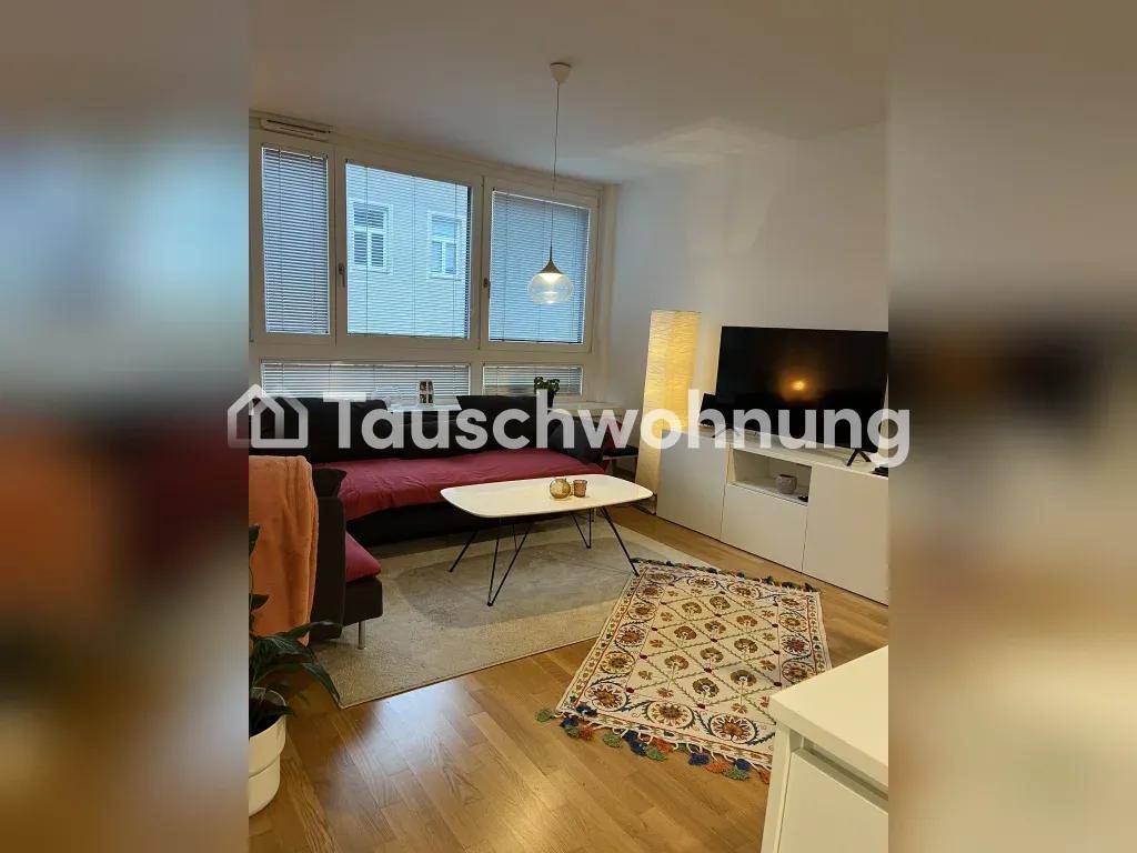 Helles Wohnzimmer mit Sofa, Couchtisch, Fernseher und großen Fenstern.