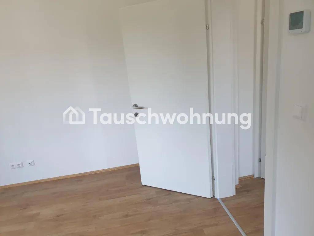 Leerer Raum mit weißen Wänden und Laminatboden, bereit für die individuelle Gestaltung und Nutzung.