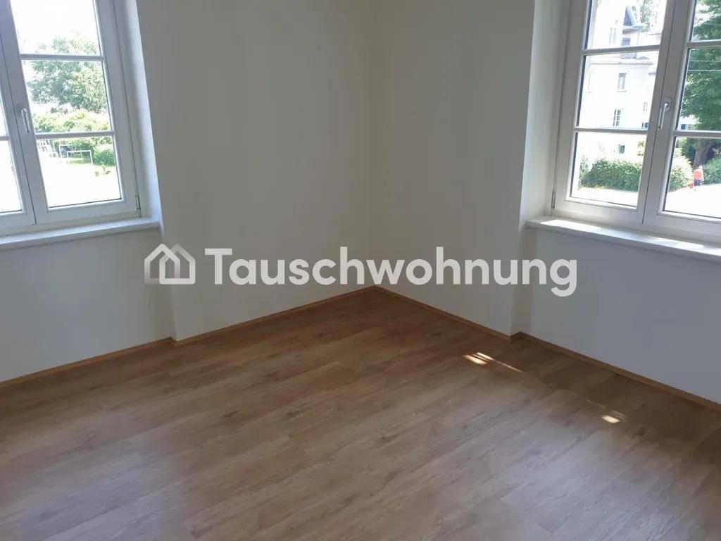 Heller Raum mit zwei Fenstern, weißen Wänden und einem gepflegten Laminatboden, bietet viel Tageslicht.