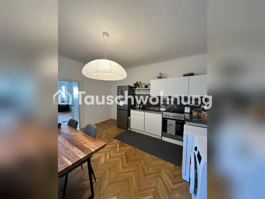 Offene Küche mit Essbereich, weißen Schränken und Holztisch.