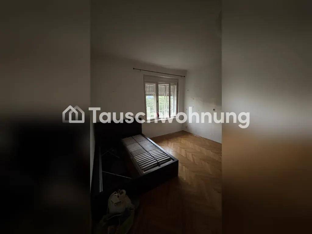 Zimmer mit Fischgrätparkettboden, einem Bettgestell und Fenster mit geschlossenen Jalousien.