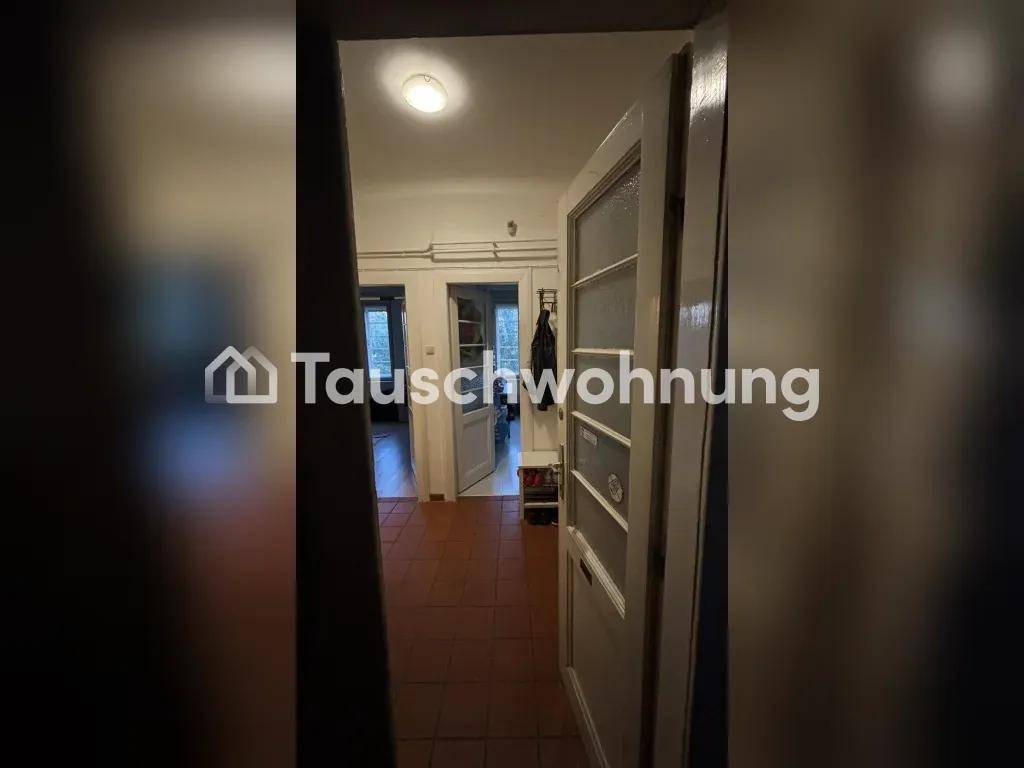 Flur mit braunen Fliesen und mehreren Türen, die zu verschiedenen Räumen führen.
