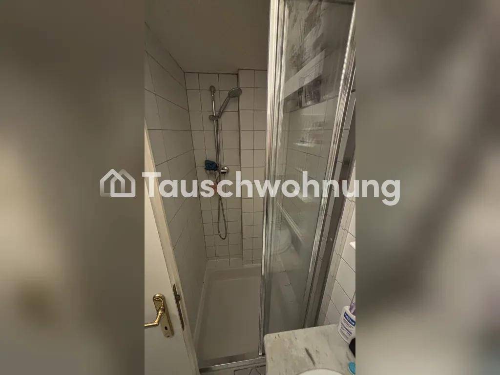 Duschkabine mit weißen Fliesen an den Wänden und einer Glastür.