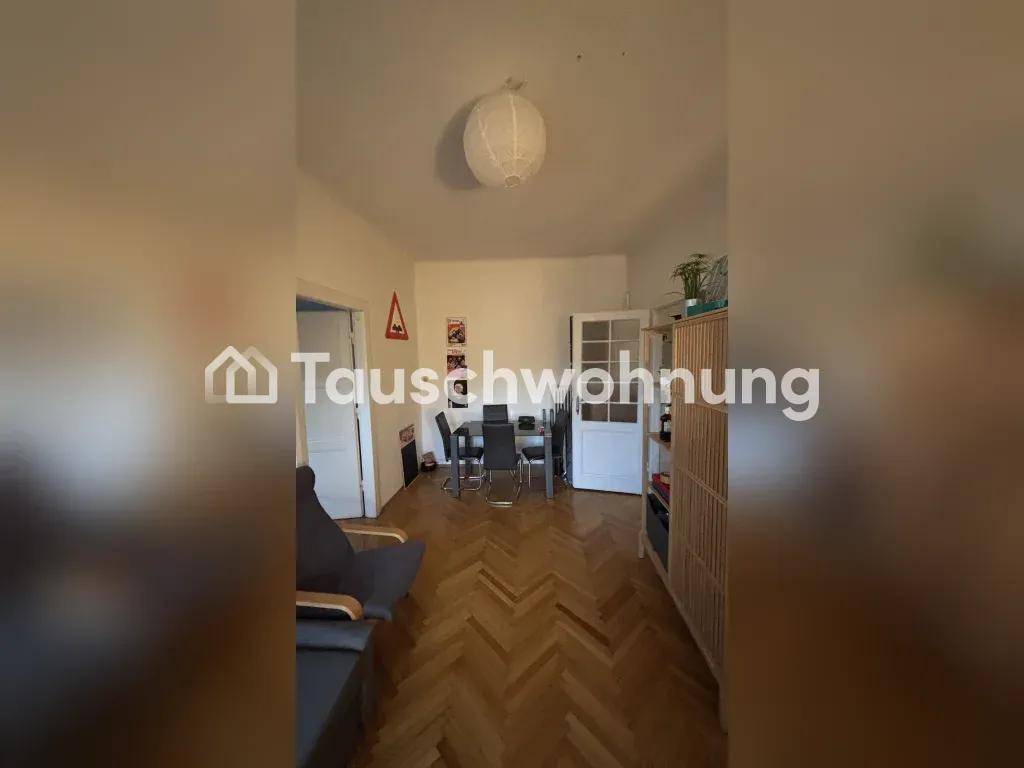 Offener Wohn-Essbereich mit Sofa, Esstisch und klassischem Fischgrätparkettboden.
