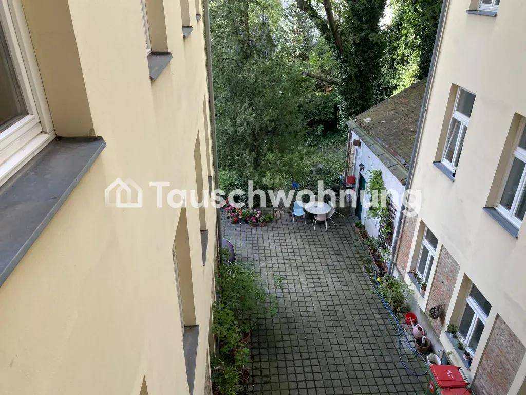 Blick von oben auf einen gepflasterten Innenhof mit Sitzgelegenheiten und Grünflächen.