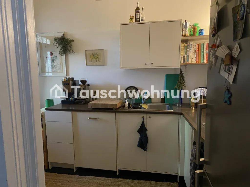 Kleine Küche mit weißen Unterschränken, Spüle und einem Kühlschrank.