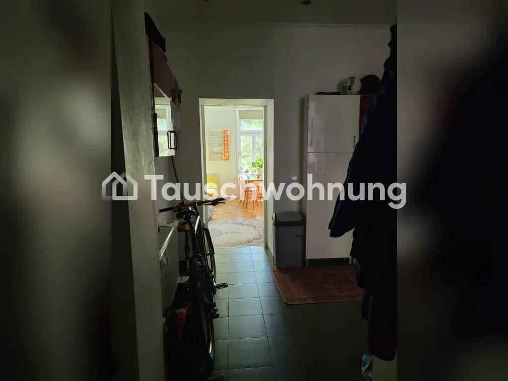 Langer Flur mit dunklen Fliesen, der zu einem helleren Raum mit Fenster führt.