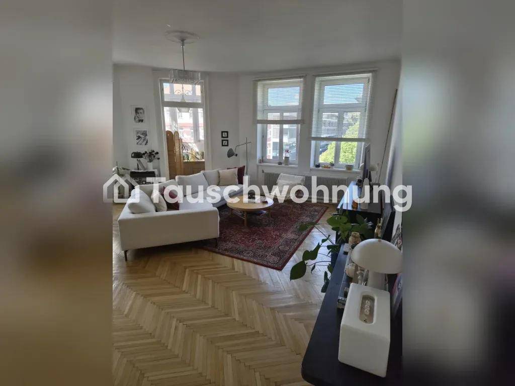 Geräumiges Wohnzimmer mit hellem Fischgrätparkett, bequemer Couch und viel Tageslicht.