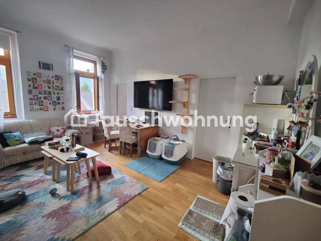 Geräumiges Wohnzimmer mit Sofa, Schreibtisch und Fernseher, heller Holzboden.