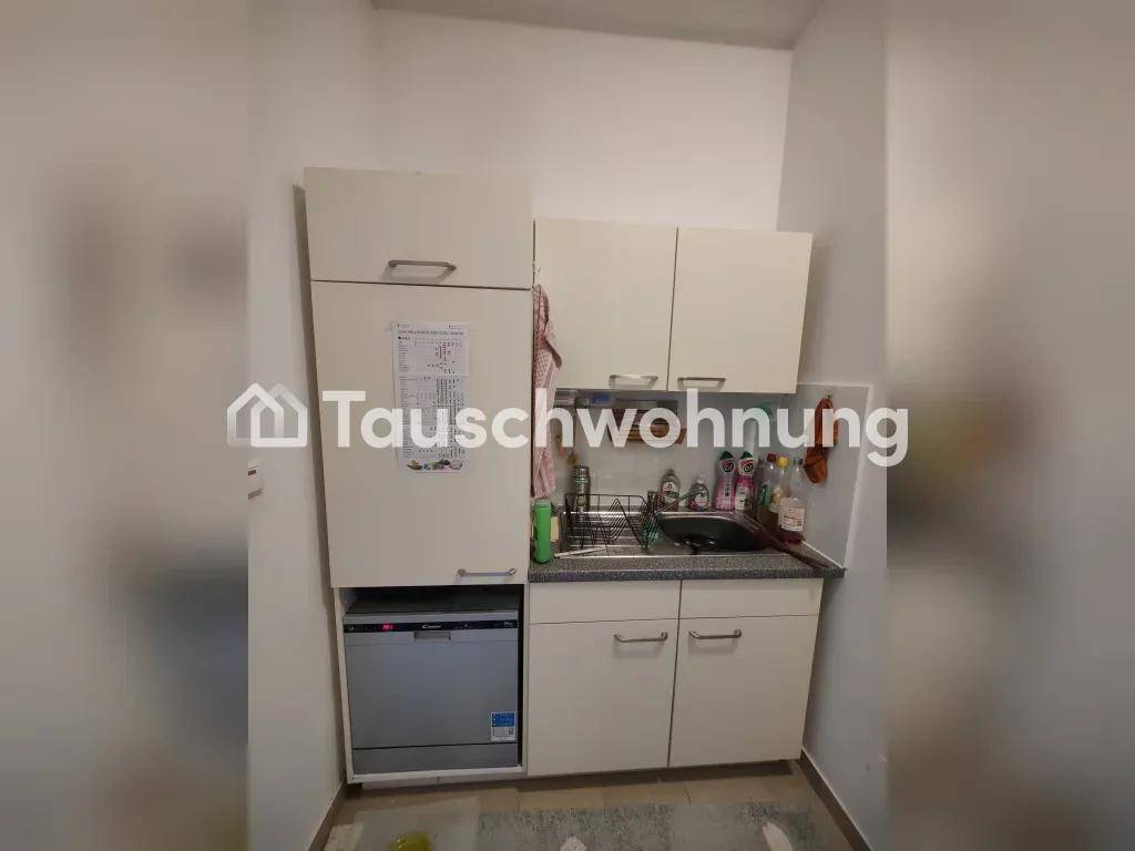 Kleine Küche mit Spüle, Geschirrspüler und Kühlschrank, ausgestattet mit weißen Schränken.