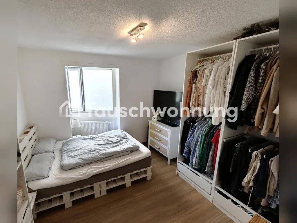 Schlafzimmer mit Palettenbett, offenem Kleiderschrank und Holzboden.