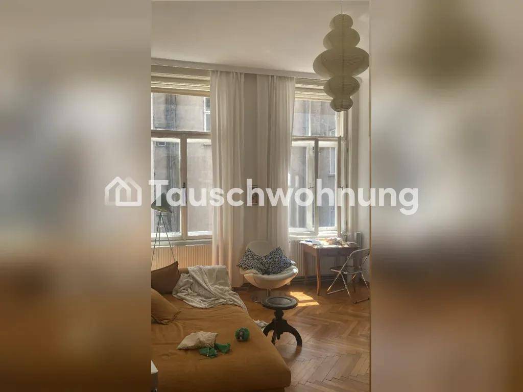 Wohnzimmer mit Fischgrätparkett, hohen Fenstern und einem Sofa.