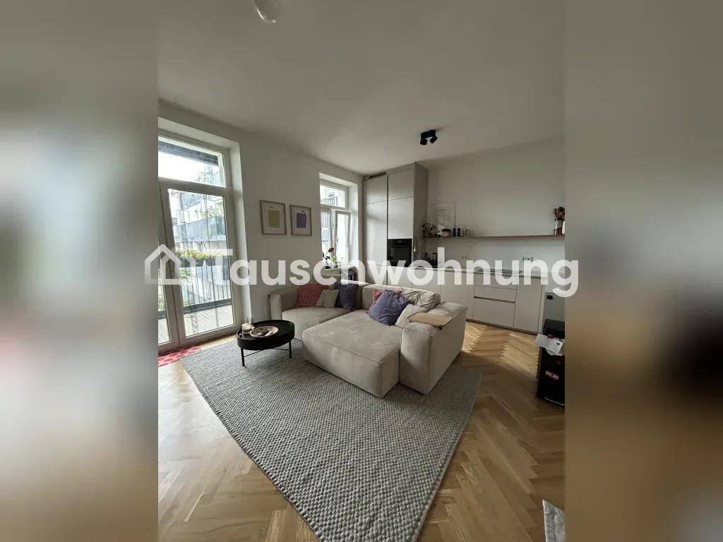 Gemütlicher Wohnbereich mit Sofa, Teppich und Blick auf die integrierte Küchenzeile.