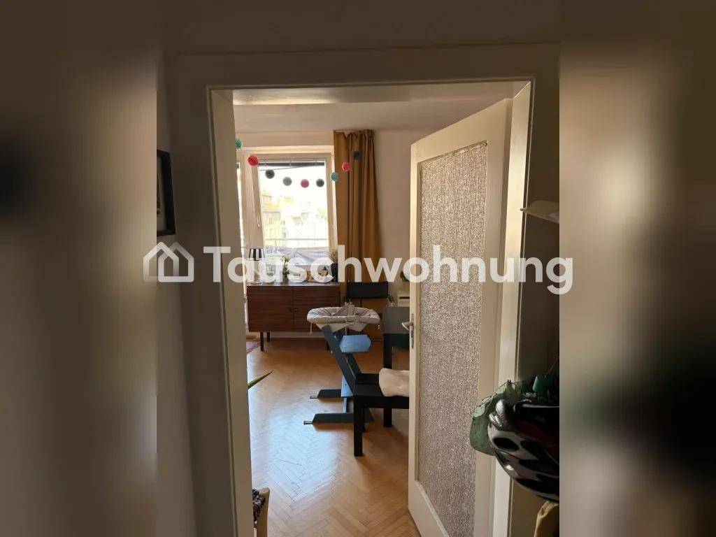 Blick durch eine Tür in einen hellen Raum mit Fenster und Holzparkettboden.