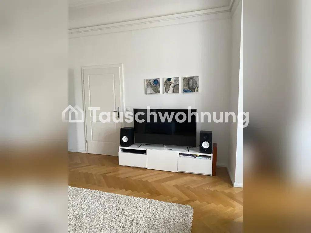 Wohnzimmer mit Fernseher, Mediamöbeln und Parkettboden.
