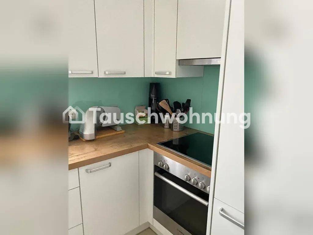 Moderne Küche mit Induktionskochfeld, Backofen und weißen Oberschränken.